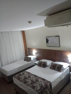 塔瓜汀加HOTEL condomínio EDIFÍCIO COMFORT TAGUATINGA FLAT的酒店客房设有两张床和两盏灯。