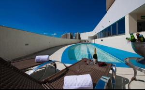塔瓜汀加HOTEL condomínio EDIFÍCIO COMFORT TAGUATINGA FLAT的一个带桌子和一瓶葡萄酒的游泳池