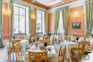 韦尔巴尼亚HOTIDAY Hotel Verbania的餐厅设有白色的桌椅和窗户。
