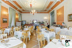 韦尔巴尼亚HOTIDAY Hotel Verbania的餐厅配有白色的桌椅和吊灯
