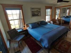 Saint Louis de KentL'Ancrage B&B and Cottages的一间卧室配有蓝色的床和椅子