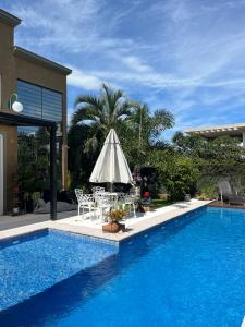 弗洛里亚诺波利斯Suite em linda casa em Jurerê internacional的一个带桌椅和遮阳伞的游泳池