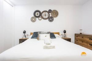 加的斯Traveler´s Dream by Cádiz Time的卧室配有白色床,墙上挂着齿轮