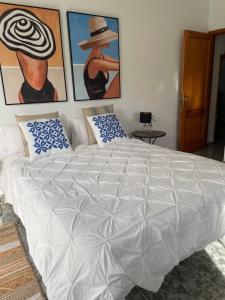 TimijiraqueAPARTAMENTO ROSALIA的卧室内的一张白色大床,配有绘画作品