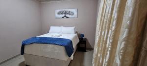 SitekiSapphire Lodge的小卧室配有一张带蓝色毯子的床