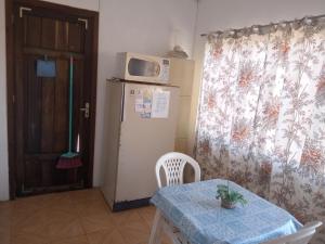 特拉曼达伊Apartamento para casal. Perto do mar的厨房配有桌子和冰箱上方的微波炉