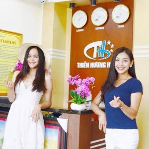 Làng LapThiên Hương Hotel的两个女人站在一个有钟的标志前
