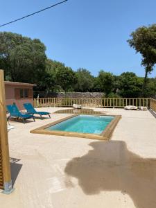 博尼法乔Petit chalet d’été avec piscine privée chauffée的庭院内的游泳池,配有2把蓝色椅子