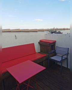 阿格德角Chambres d'Hotes NATURISTE, Village Naturiste Cap d'Agde, Draps, Serviette, Café, Menage inclus en fin de sejour的阳台的红色长椅和椅子