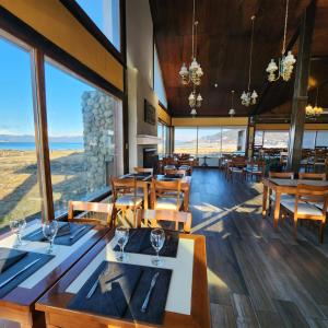 乌斯怀亚Tolkeyen Ushuaia Hotel的餐厅设有桌椅和大窗户。