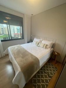 伊塔佩马Apart moderno 3 suites 2 vagas de garagem e quadra do mar的一间卧室设有一张大床和一个窗户。