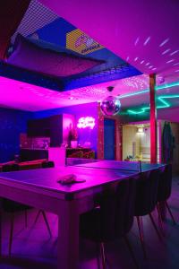 拉卢维耶尔Capsule Boogie-Woogie - JACUZZI - SAUNA - BILLARD - JEUX - ECRAN GÉANT - FILET SUSPENDU - NETFLIX的一间设有酒吧的房间,配有紫色的灯光和椅子