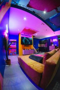 拉卢维耶尔Capsule Boogie-Woogie - JACUZZI - SAUNA - BILLARD - JEUX - ECRAN GÉANT - FILET SUSPENDU - NETFLIX的一间卧室配有一张大床和紫色照明