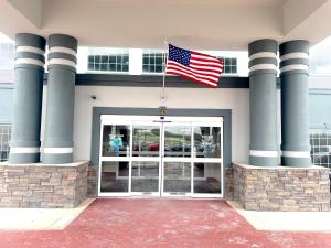 圣安东尼奥圣安东尼奥阿拉莫区速8酒店的悬挂在建筑物前门的美国国旗