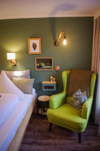 圣安东阿尔贝格打谷场酒店的一间卧室配有一张床和一把绿色椅子