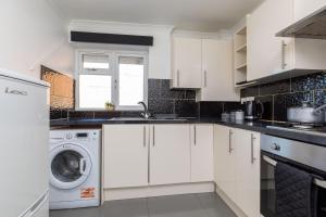 克劳利19A Apartment- Stylish & Cozy 1BR in The Heart of Crawley的厨房配有白色橱柜、洗衣机和烘干机