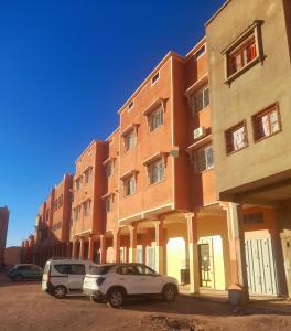 瓦尔扎扎特Appartement Sariq Ouarzazate的两辆汽车停在大楼前
