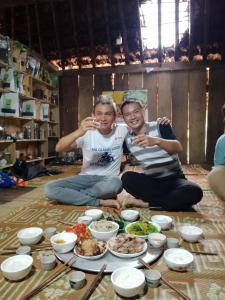 河江Ha Giang Yolo House and Loop Tours的两个坐在地板上的人,有盘子的食物