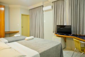 里奥韦尔迪Honorato Hotel的酒店客房设有两张床和一台平面电视。