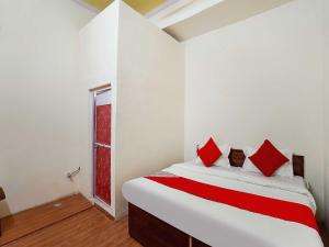 法里达巴德The Golden Crown的一间卧室配有一张带红色枕头的床和一扇窗户
