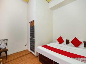 法里达巴德The Golden Crown的一间卧室配有一张带红色枕头的床和一把椅子