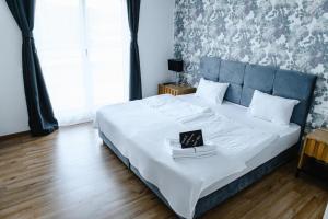 施瓦格明德Hotel Flora的一间卧室配有一张白色大床和蓝色床头板