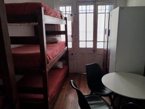 圣地亚哥Wild Bellavista Hostel的客房设有两张双层床和一张桌子及椅子。