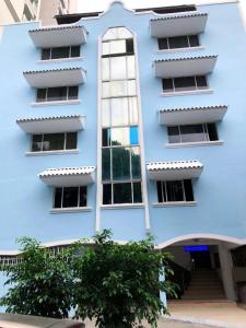 巴拿马城HOTEL BLUE COSTA Panama的前面有棵树的蓝色建筑