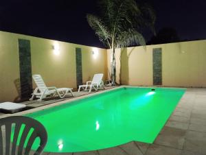 圣何塞Sol de Belen的游泳池,晚上带两把椅子和棕榈树