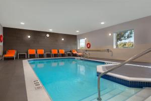 巴里巴里智选假日套房酒店的一座游泳池,位于酒店客房内,配有橙色椅子