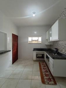 大伊瓜巴Casa em iguaba grande的厨房配有白色橱柜和红色地毯。