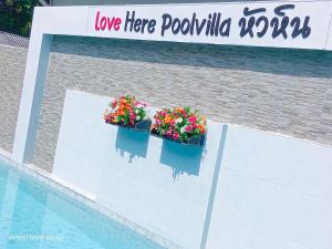 华欣Love Here Poolvilla หัวหิน的游泳池边的两盒花