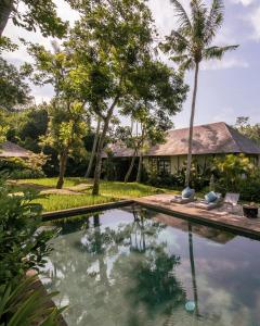 乌布Villa Bedulu Cliff Estate Ubud - Wood Side的棕榈树屋前的游泳池