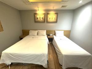首尔Urban Nest Hotel的配有白色床单的客房内的两张床