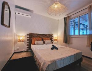 珀蒂蒂勒Lilie location sud的一间卧室配有一张大床和一个吊灯。
