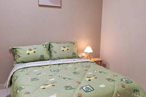 哥打丁宜Shmawai Homestay Kota Tinggi的一间卧室配有一张带绿色棉被的床