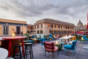 罗马citizenM Rome Isola Tiberina的一座配有桌椅的庭院和一座建筑