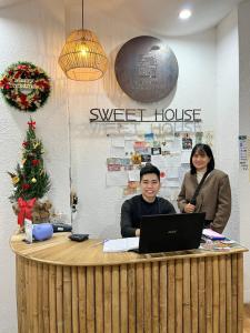 顺化Hue Sweethouse 1 Homestay的坐在台子里的男人和女人,手提电脑