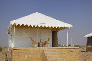 斋沙默尔Hotel Shahiraj Jaisalmer的白色帐篷,配有两把椅子和一张桌子