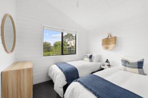 HaruruPaihia Coastal 2 Bedroom Cottages的白色客房的两张床,设有窗户