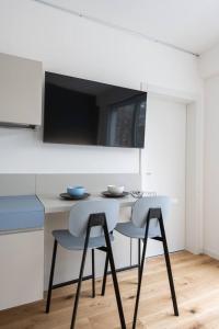 特伦托Casa Kaleido的厨房配有带2把椅子的桌子和电视。