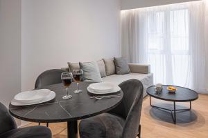 雅典Kriel Suites by LIV Homes的客厅配有桌子和两杯葡萄酒