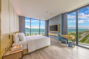 岘港Awaken Da Nang Hotel的酒店客房配有一张床、一张书桌和一台电视。