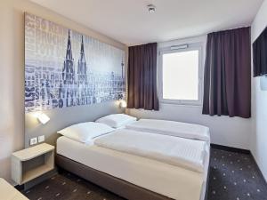 科隆B&B Hotel Köln-West的卧室配有两张床,墙上挂着一幅画