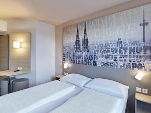 科隆B&B Hotel Köln-West的卧室配有白色的床,墙上挂着一幅画