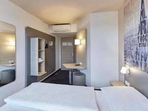 科隆B&B Hotel Köln-West的一间卧室配有两张白色的床和一张书桌