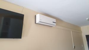 曼齐尼Manzini, Park Vills Apartment, No 103的电视旁墙上挂有壁挂式空调器