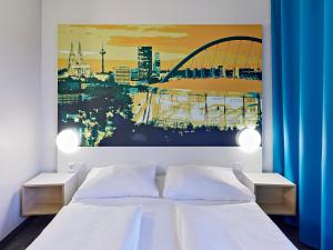 科隆科隆博览会B&B酒店的卧室配有一张白色床,墙上挂有绘画作品