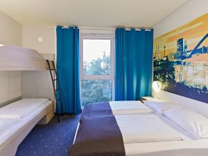 科隆科隆博览会B&B酒店的一间卧室设有两张床,窗户配有蓝色窗帘