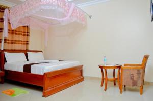 达累斯萨拉姆银色天堂酒店的一间卧室配有一张带桌子和椅子的天蓬床